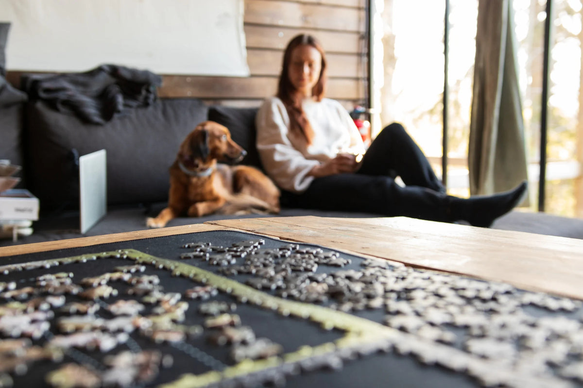 Puzzle auf einem Tisch, Mensch und Hund im Hintergrund